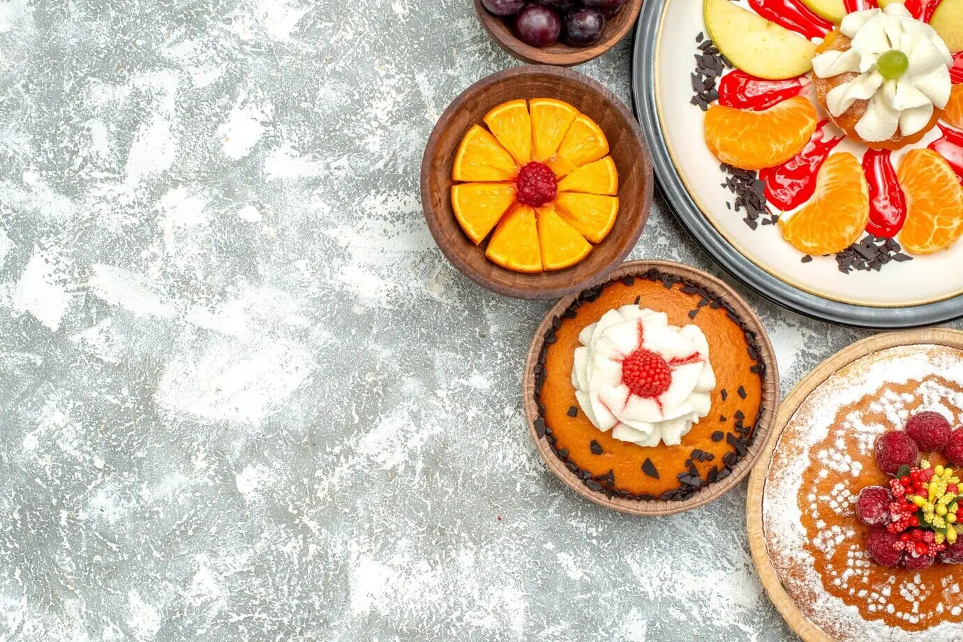 Top view of a small creamy cake alongside raspberry cake and a pie on a white surface; fruit, sweet cake, pie, sugar biscuit.